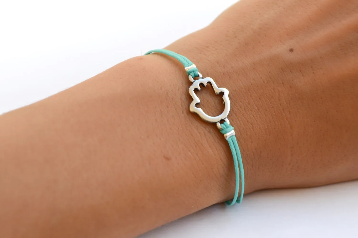 Turquoise cord bracelet with a silver Hamsa charm, evil eye protection