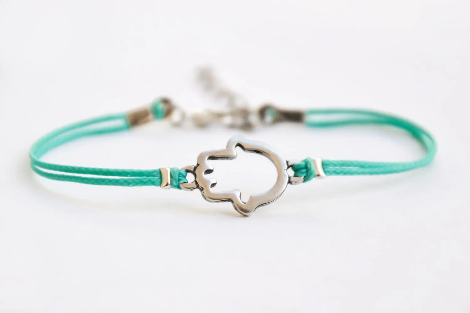 Turquoise cord bracelet with a silver Hamsa charm, evil eye protection